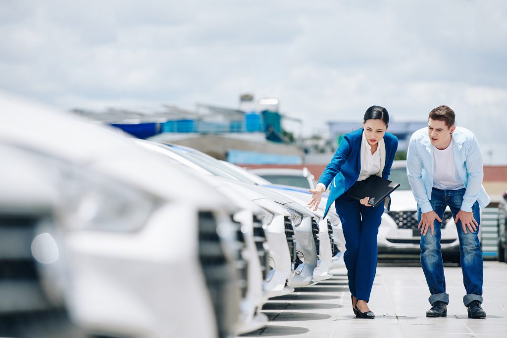 Vendeuse automobile montrant les différents modèles de véhicules au jeune client