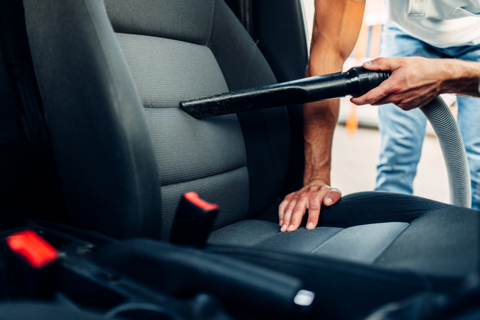 Homme nettoyant l'intérieur de sa voiture avec un aspirateur aidant à préserver la qualité le plus longtemps possible