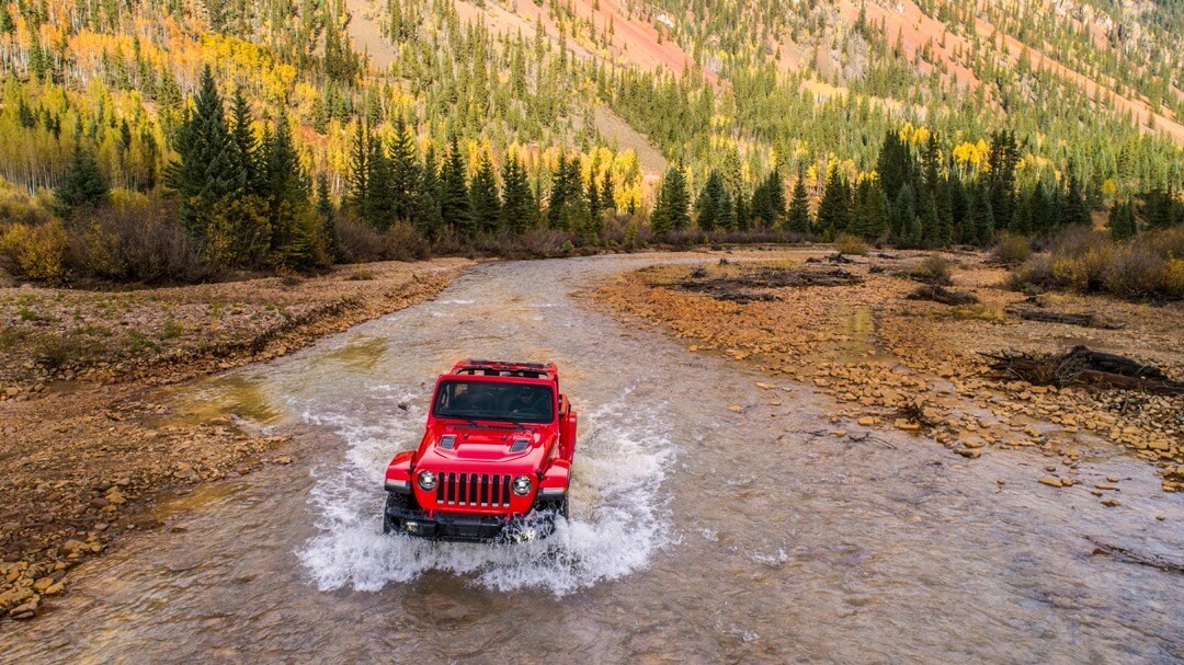 vue frontale d'un Jeep Wrangler 2023 dans un cours d'eau en montagne