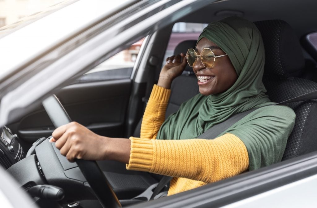 Femme contente de conduire sa nouvelle voiture