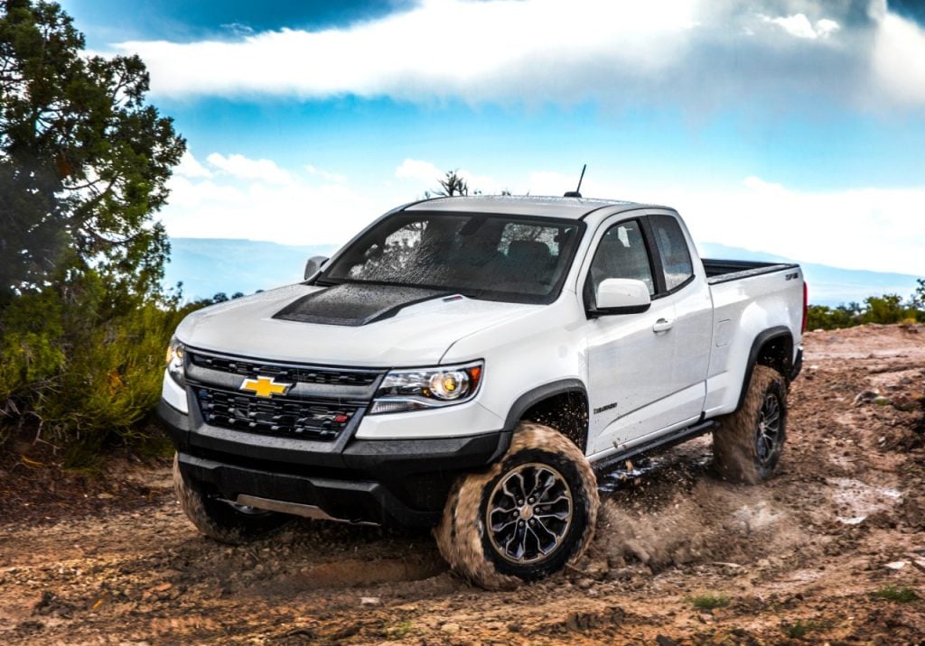 Chevrolet Colorado ZR2 2017 blanc roulant dans la boue dans la nature sous un ciel semi nuageux