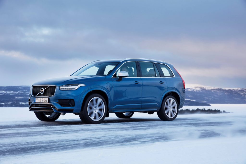 Volvo XC90 T8 R-design hybride 2017 bleu conduisant sur une route glaçée pendant la saison hivernale avec des montagnes en arrière-plan