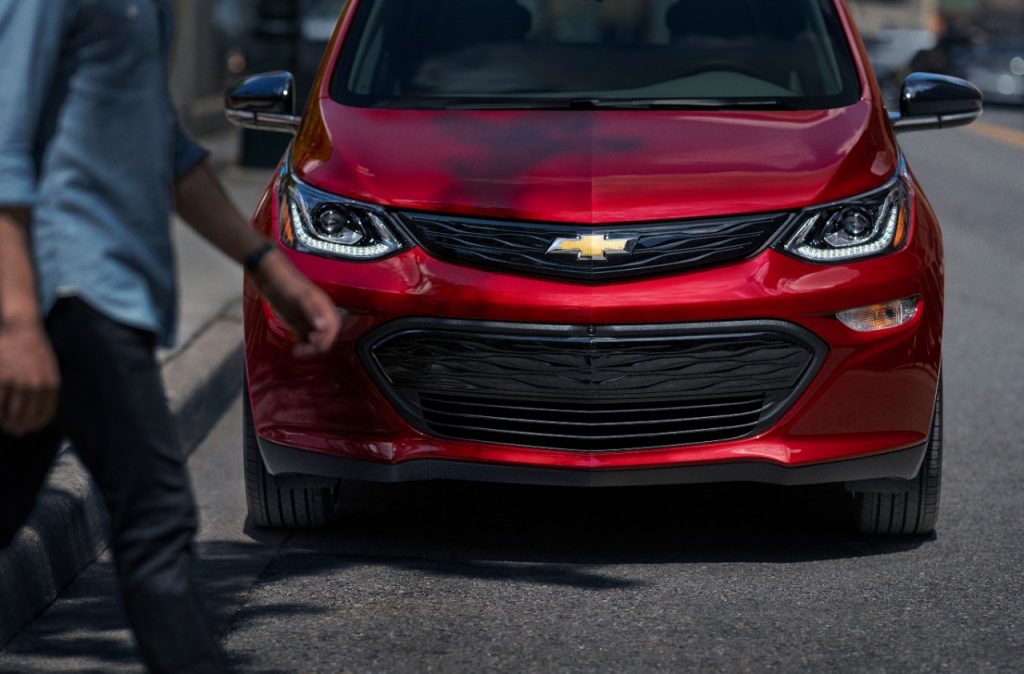 vue avant de la Chevrolet Bolt EV 2020 rouge garé dans la rue avec piéton qui traverse