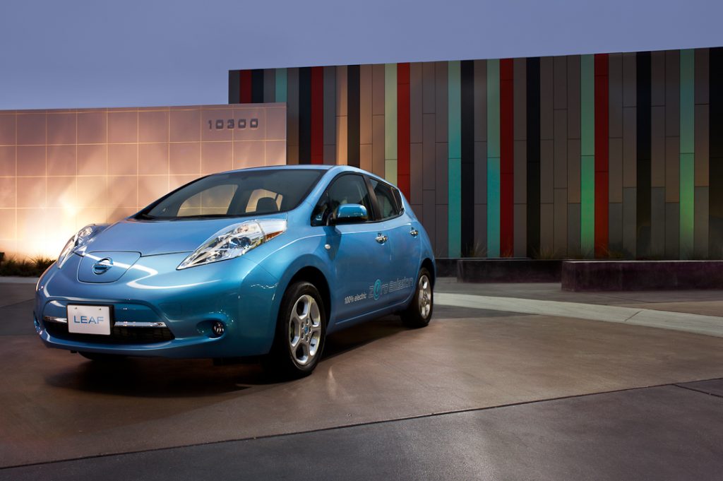 Nissan Leaf 2011 bleu pâle garé devant un mur moderne d'une maison