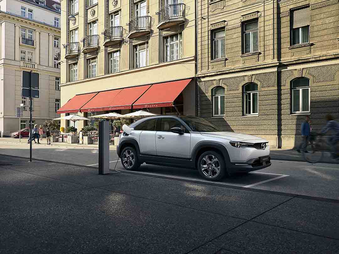 vue latérale avant du Mazda MX-30 VÉ 2022 à une borne de recharge