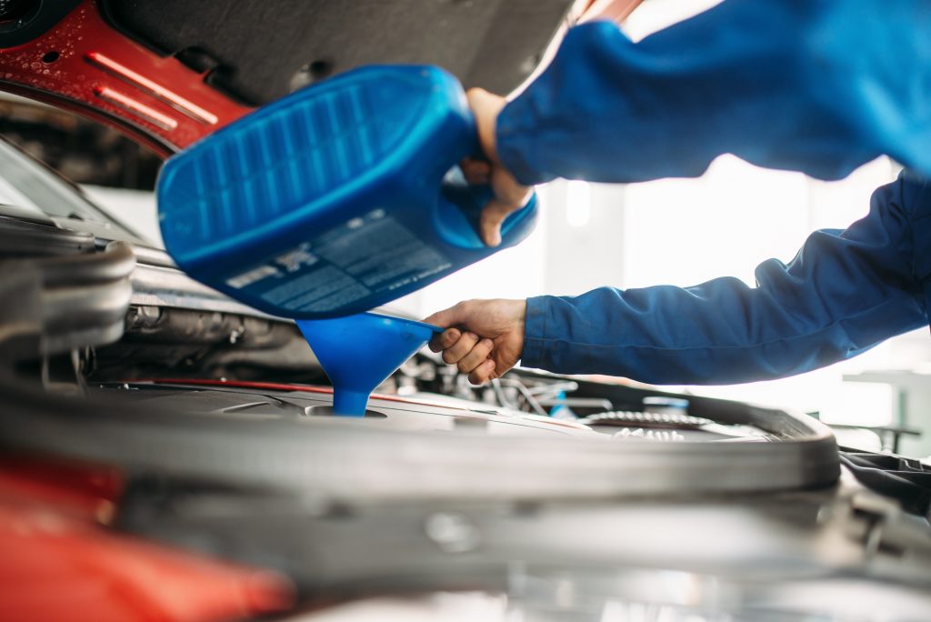 mécanicien effectuant un changement d'huile dans le moteur de la voiture